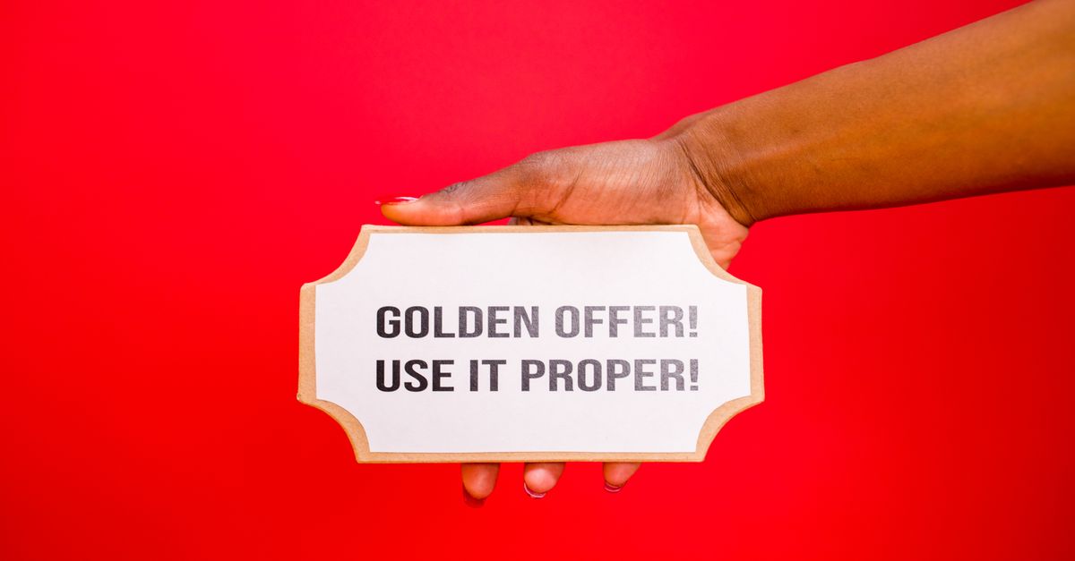 A hand holds a 'Golden Offer' sign on a vibrant red background, symbolizing deals and promotions.